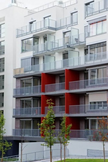 Moderní bytový dům s venkovním zábradlím balkonů a teras s příčkovými výplněmi.