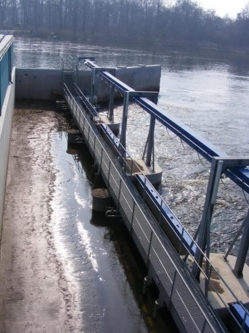 Vodní elektrárna s konstrukcí a vodním tokem na pozadí.