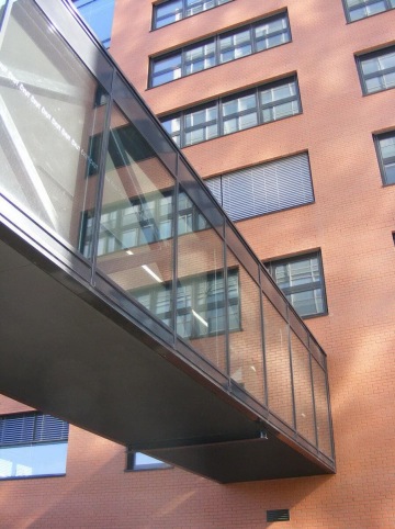 Prosklený most mezi dvěma cihlovými budovami ČVUT Praha Fakulta stavební s moderními okny.