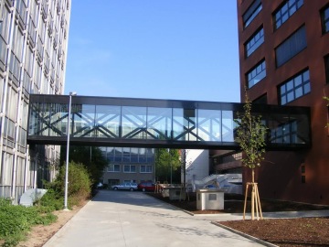 Prosklená lávka spojující dvě moderní budovy ČVUT Praha Fakulta stavební pod modrou oblohou.