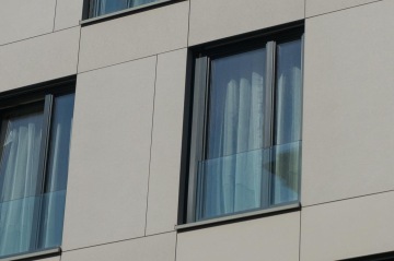 Francouzské okno moderní budovy s zataženými závěsy a balkónovým sklem.