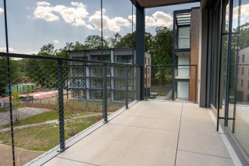 Balkonové kovové zábradlí s výplní z nerezové sítě.