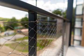 Balkonové kovové zábradlí s výplní z nerezové sítě.