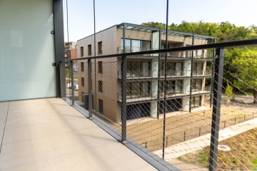 Balkonové kovové zábradlí s výplní z nerezové sítě.