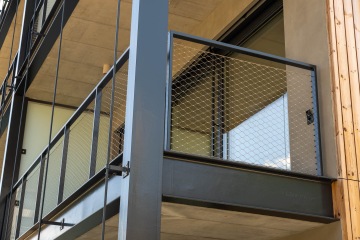 Balkonové kovové zábradlí s výplní z nerezové sítě.