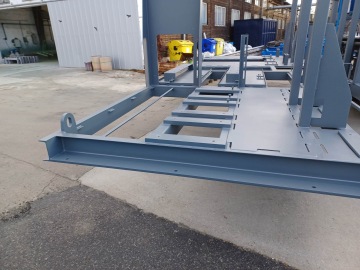 Kovový rám na betonové ploše v industriálním prostředí.