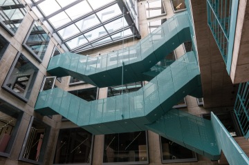 Moderní schodiště s ocelovou perforovanou konstrukcí v tyrkysové barvě.