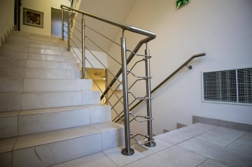 Schodiště s nerezovým zábradlím v interiéru.