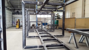 Svařované ocelové konstrukce v tovární hale, viditelné velké rámové segmenty.