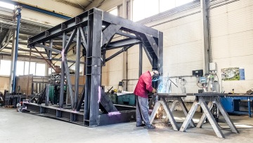 Osoba svařuje ocelovou konstrukci v průmyslové dílně.