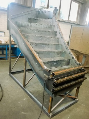 Stabilní kovová konstrukce schodiště ve výrobní hale.