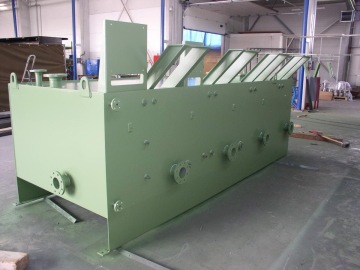 Zelený průmyslový kovový box s otvory a poklopy uvnitř výrobní haly.