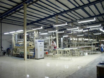 Stroj pro výrobu sanitární keramiky technologií tlakového lití do porézních plastových forem v tovární hale.