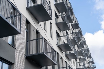 Balkony moderního bytového domu proti modré obloze.