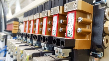 Řada průmyslových ventilů s označením na přední straně v technickém prostředí.