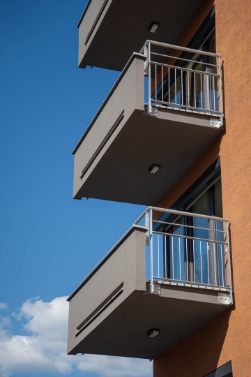 Balkony moderního bytového domu proti modré obloze.